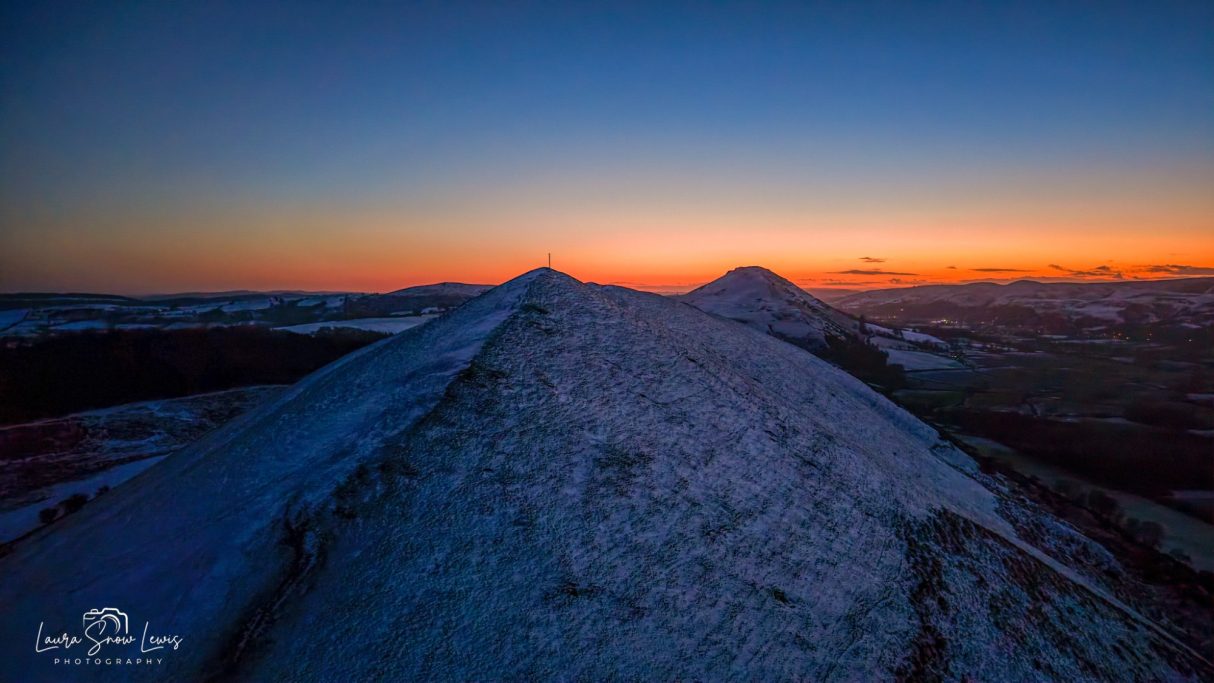 Dusk view of mountainous peaks with a vibrant sunset in the background.