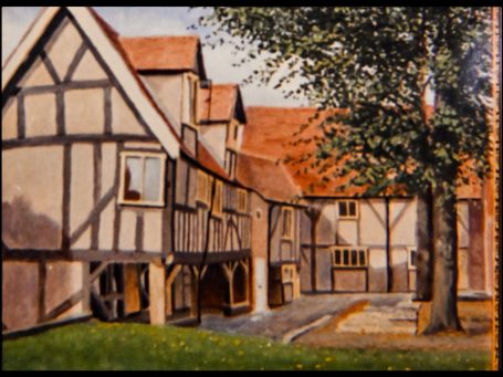 A historical timber-framed building with a courtyard and trees.